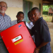 Lehrer Karsten Riggert mit tansanischen Schülern beim Auspacken eines Sunny Mini Centrals