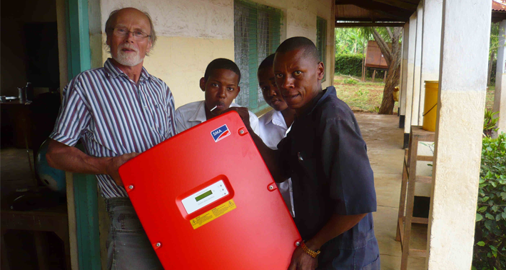 Lehrer Karsten Riggert mit tansanischen Schülern beim Auspacken eines Sunny Mini Centrals