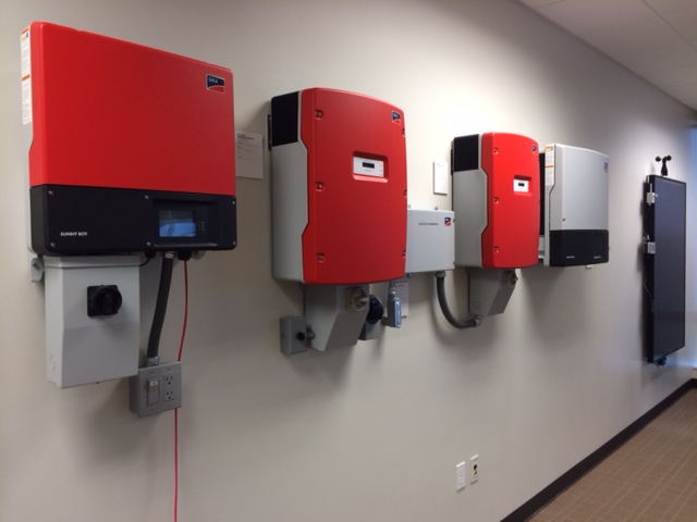Inverters lined up along the Solar Academy's wall, ready for testing.