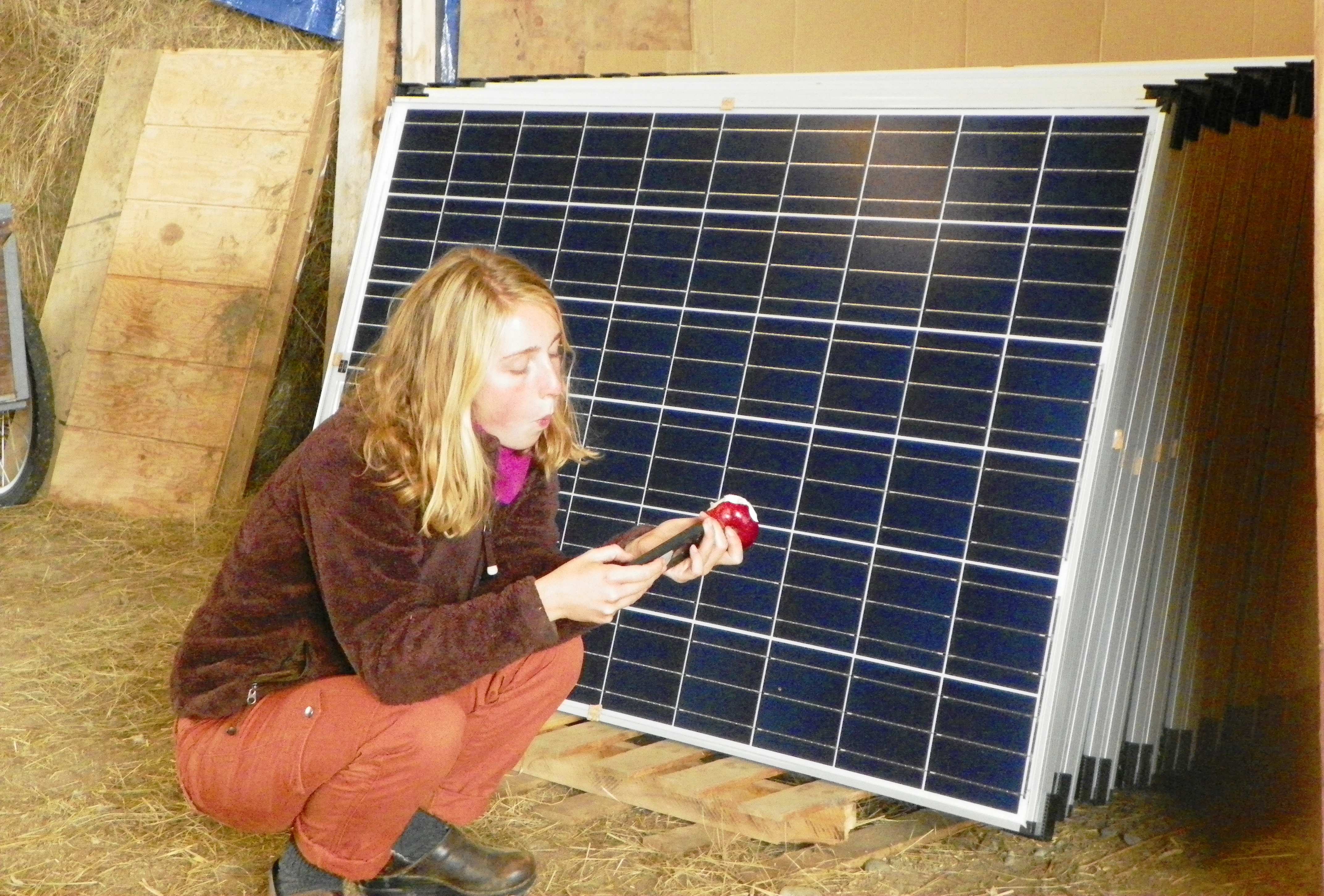 A student takes a break from the barn build next to the solar modules, waiting for installation.