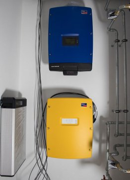 Ein blauer Sunny Tripower Solar-Wechselrichter und ein gelber Sunny Island-Batterie-Wechselrichter sorgen dafür, dass der Solarstrom vom Dach für den Verbrauch der elektrischen Geräte zur Verfügung steht oder in der LG-Batterie gespeichert wird. 