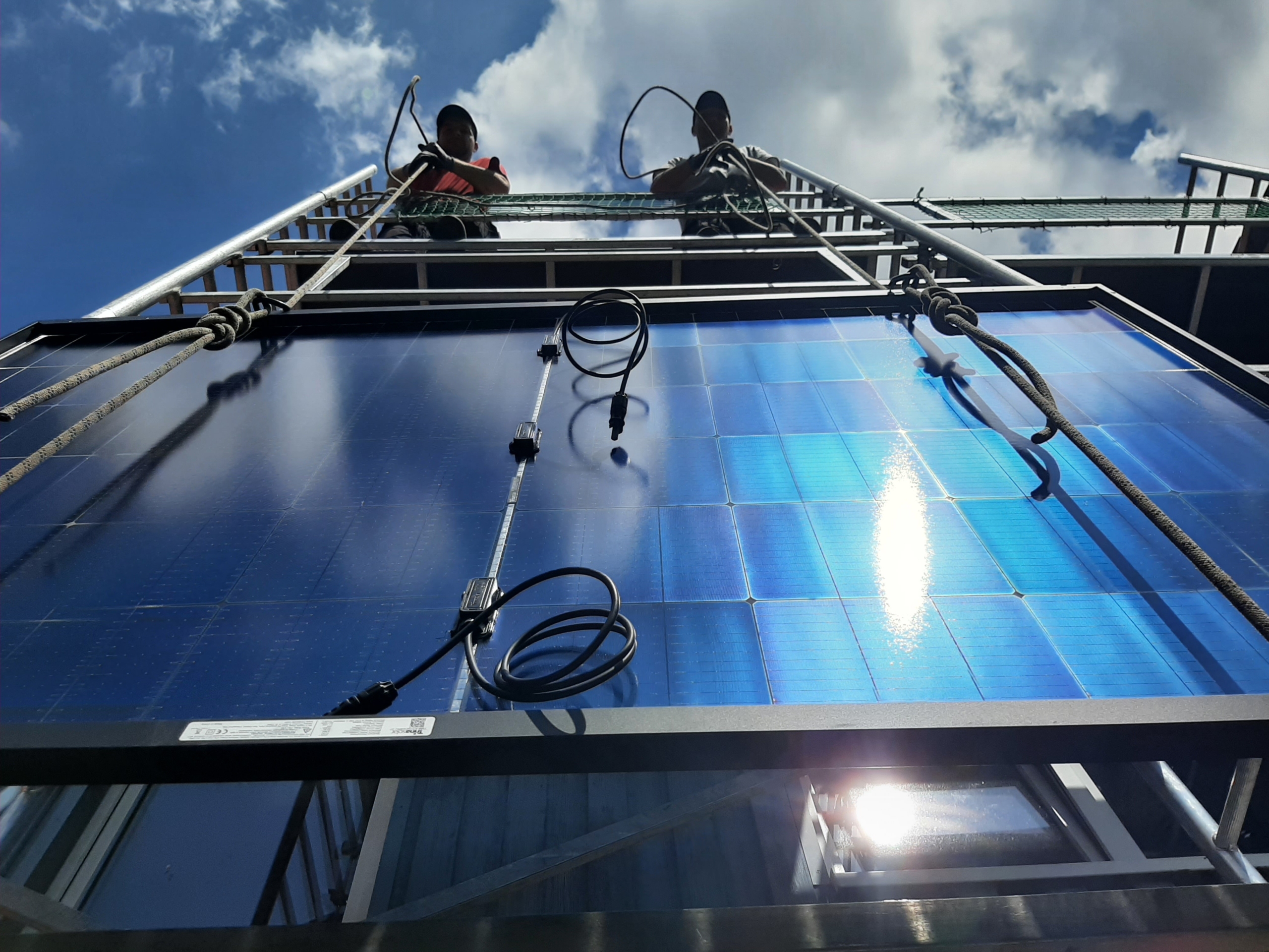 Dachdecker ziehen Photovoltaik-Module auf ein Hausdach.